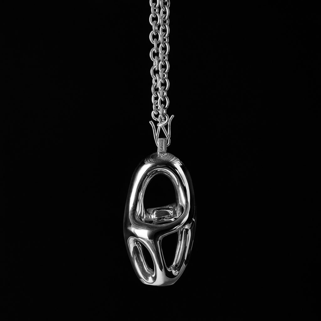 A silver version of Celine's Ptolomee II pendant, an abstact ovular sculpture originally by Jean Arp, hangs from a silver chain