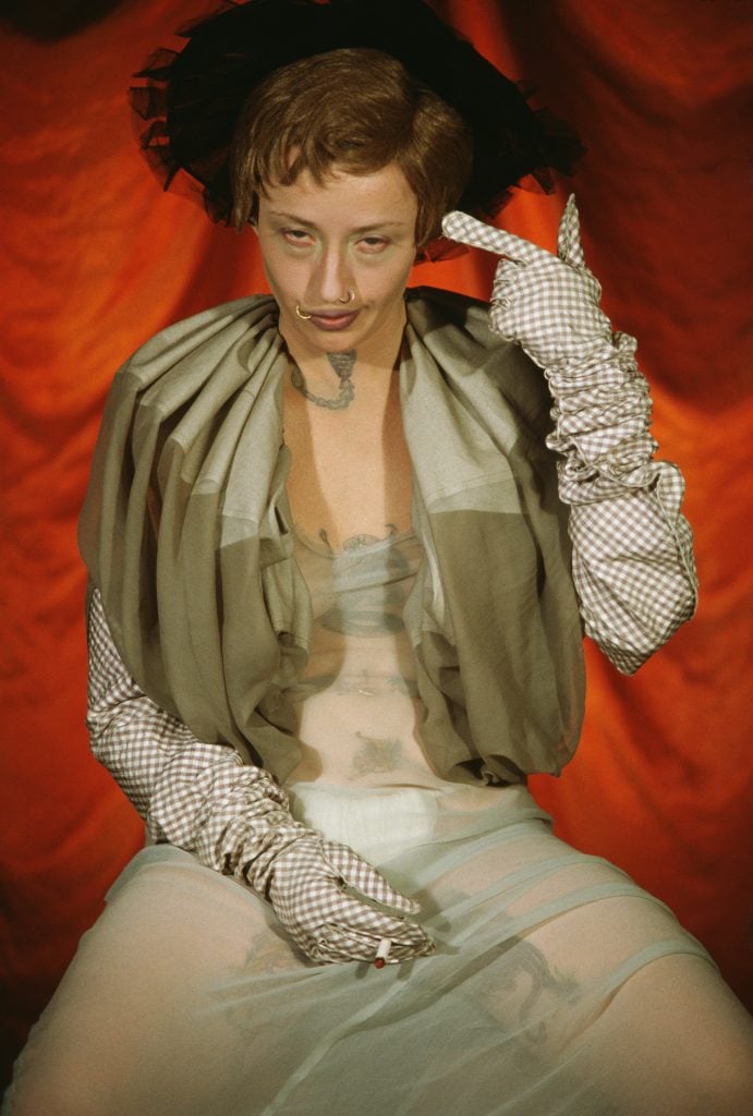 a woman in extravagant clothing against a red background