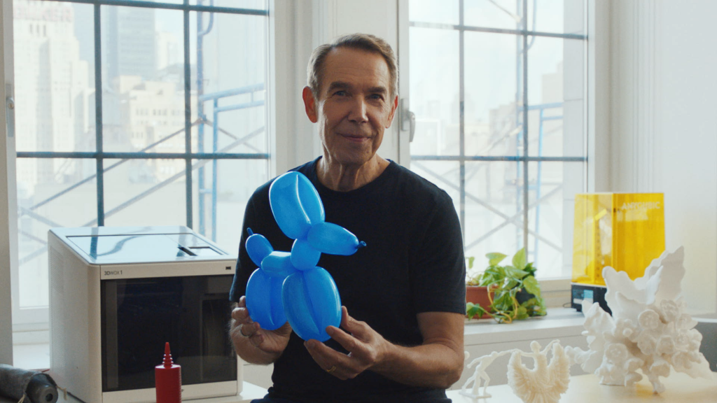 a man sits in the center of the image with a blue balloon dog in hand