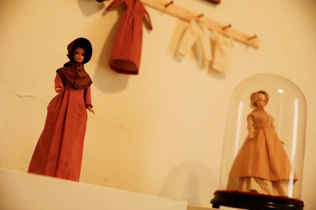 Dolls wearing Shaker clothing, one in a balaclava