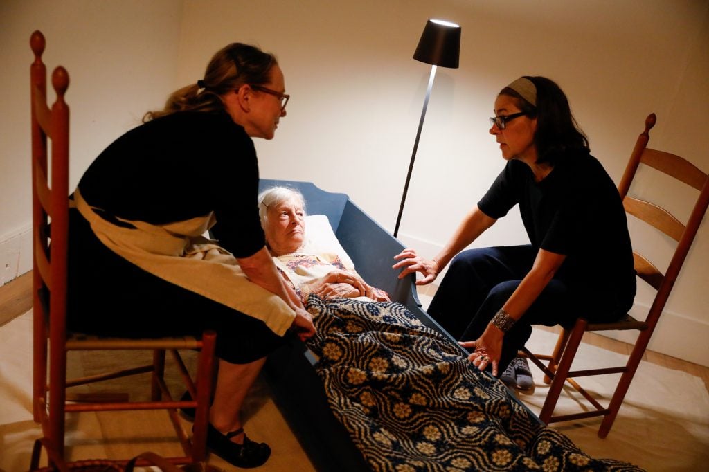 Joan Jonas lying in an adult cradle with Suzanne on one side and Annie on the other