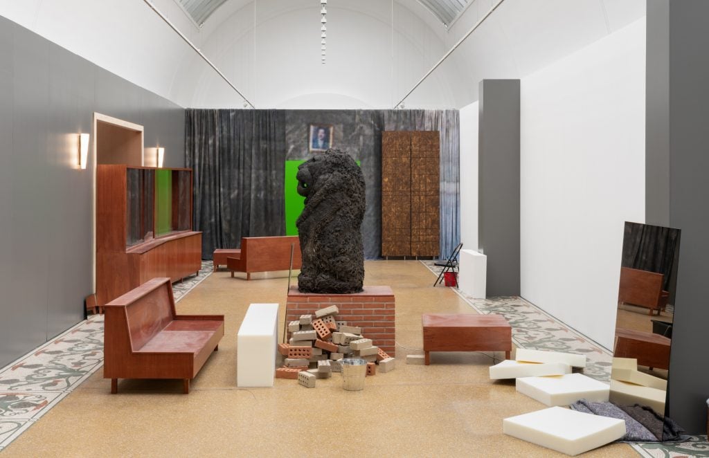 a room in a gallery full of objects, some of which are like furniture and others large sculptural pieces