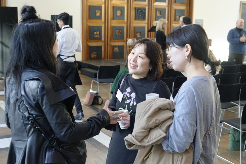 Attendees networking and chatting after a conference panel discussion.