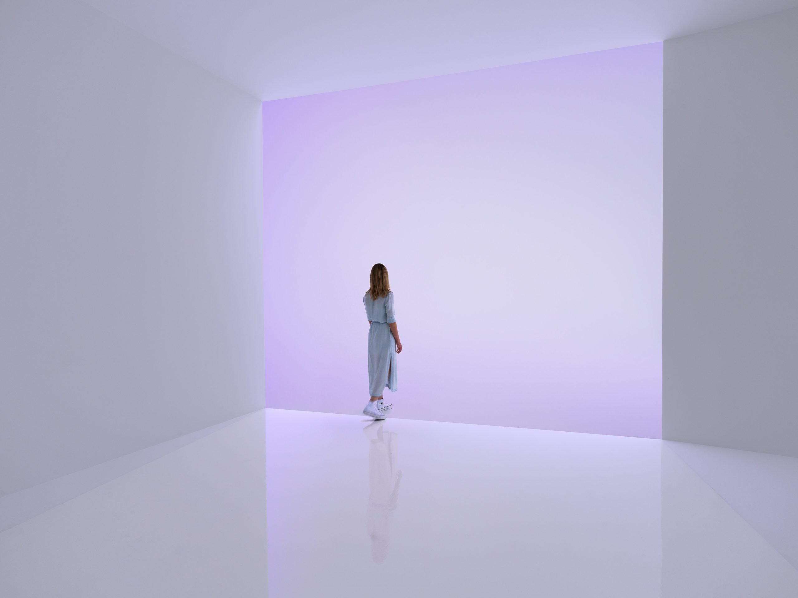 a figure steps into a violet abstract haze in a contemporary art galley