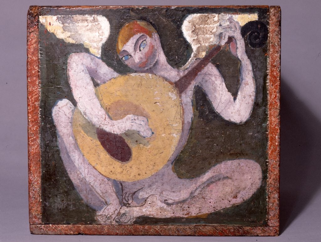 a wooden box, on the side we can see there is pained a stylized nude purple figure with angel wings that is holding a large guitar and looking at us 