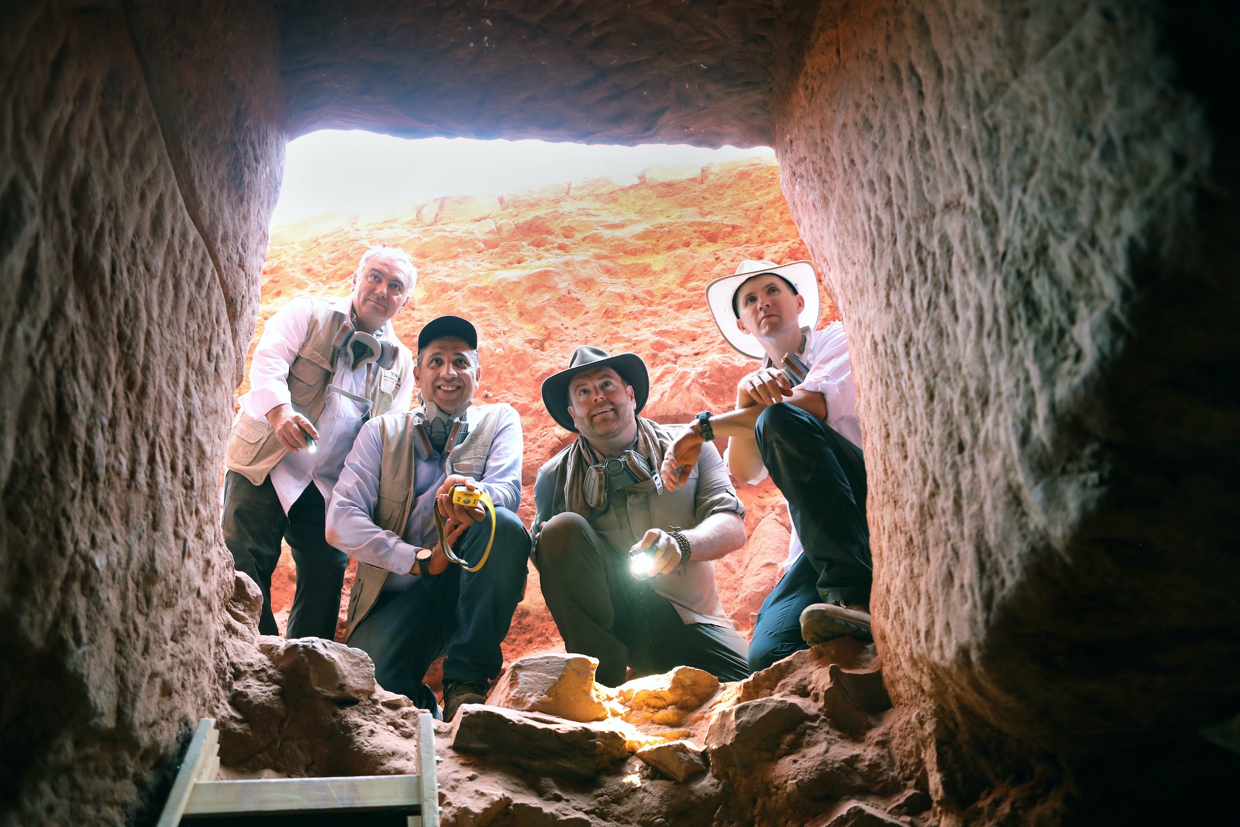 Four archaeologists looking into the tomb, shown from beneath