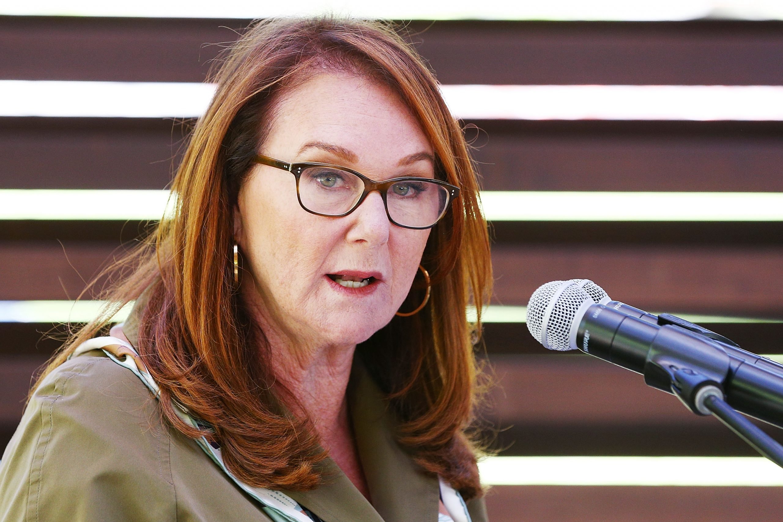 A white lady speaks into two microphones