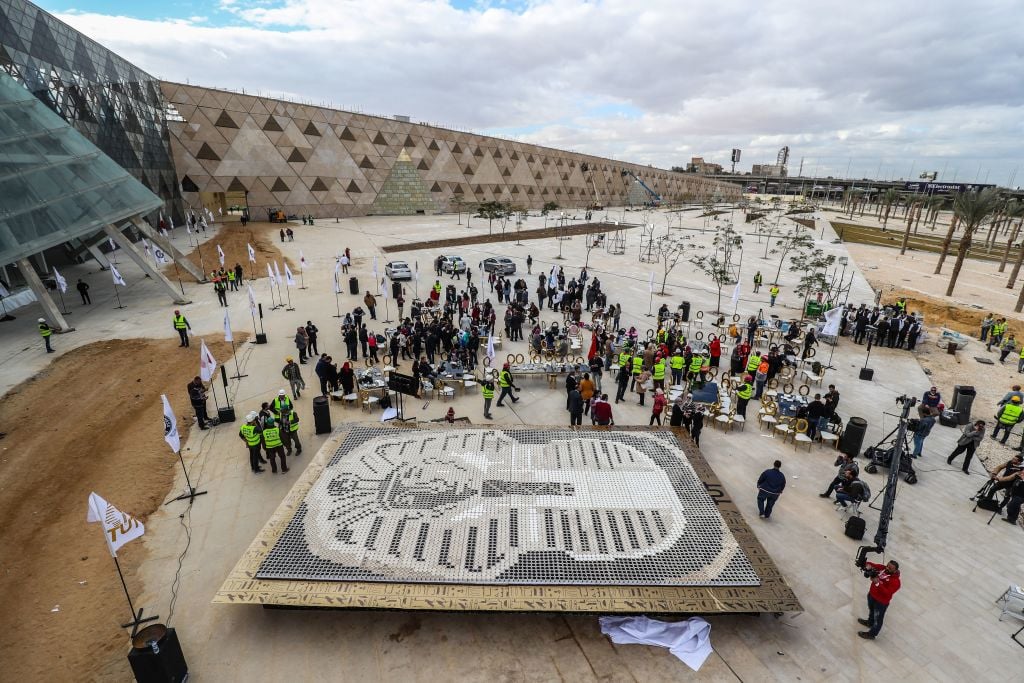 people gather around a mosaic of a pharaoh