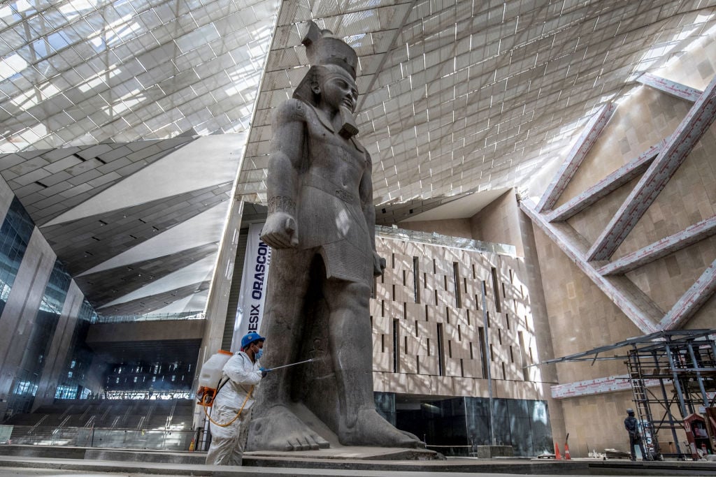 a large egyptian statue inside a grand museum hall