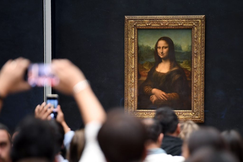 a crowd of visitors tries to take a picture of the mona lisa