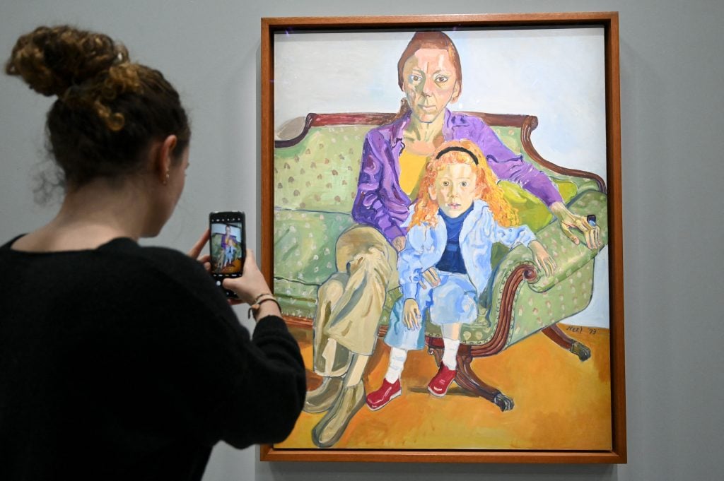 a woman takes a picture of a painting of two women