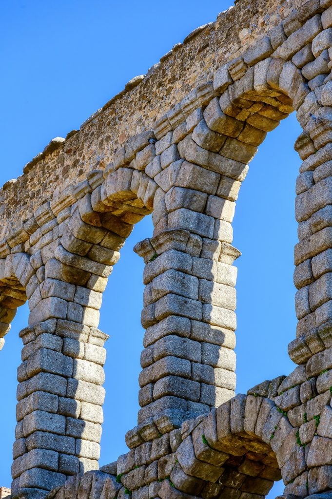 a close up of some arches in the aqueduct with a blue sky background