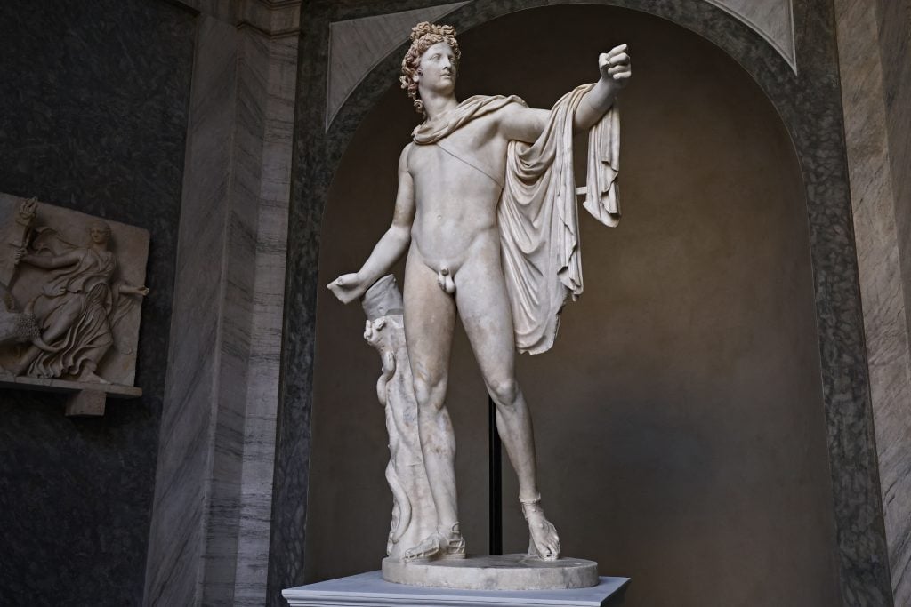 he Apollo Belvedere, a renowned marble statue of the Greek god Apollo, standing gracefully with detailed musculature and flowing drapery