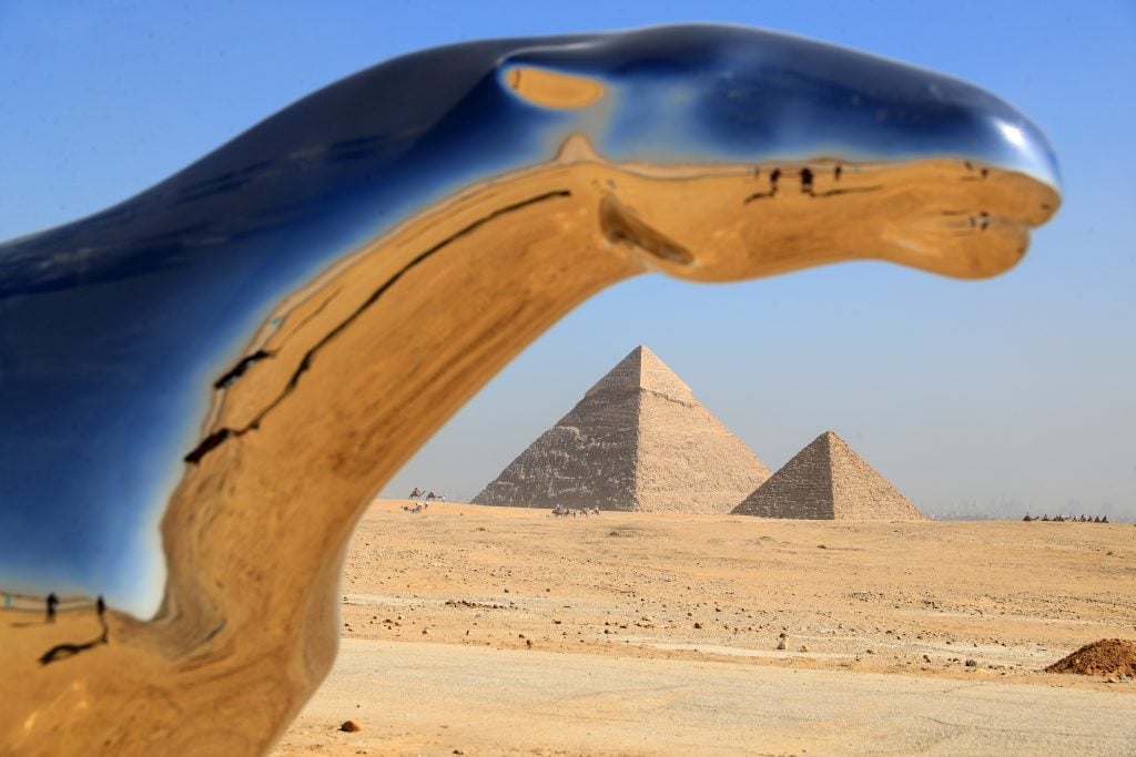 sleek sculptures of panthers are seen against the backdrop of pyramids