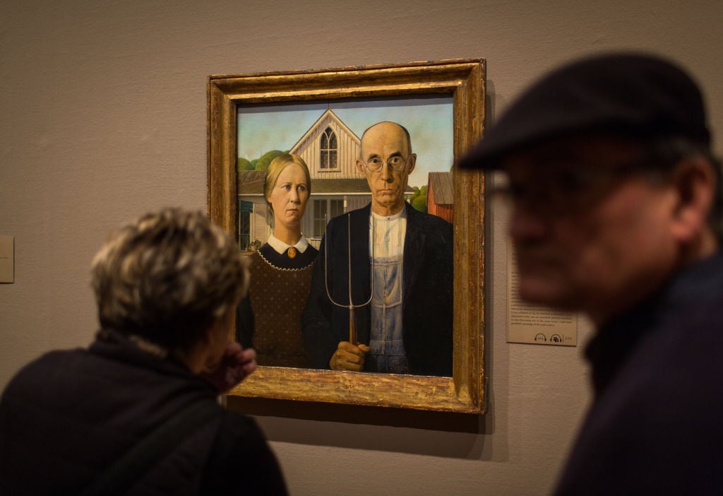 two people looking at a painting on a wall in a museum