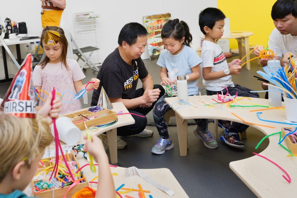 a group of children make art at round table