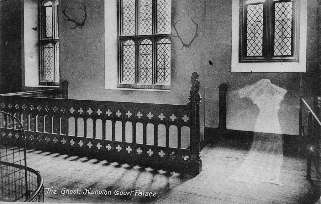 a black and white photograph of a medieval-style interior with a transparent, white ghostly figure of a woman transposed over the interior to the right