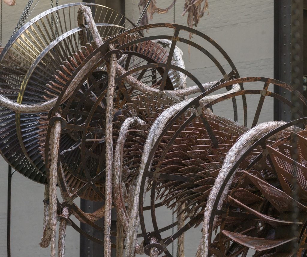 a metal turbine, a mechanical device, that is made of rusted metal and slung over with pieces of damp, dirty rope