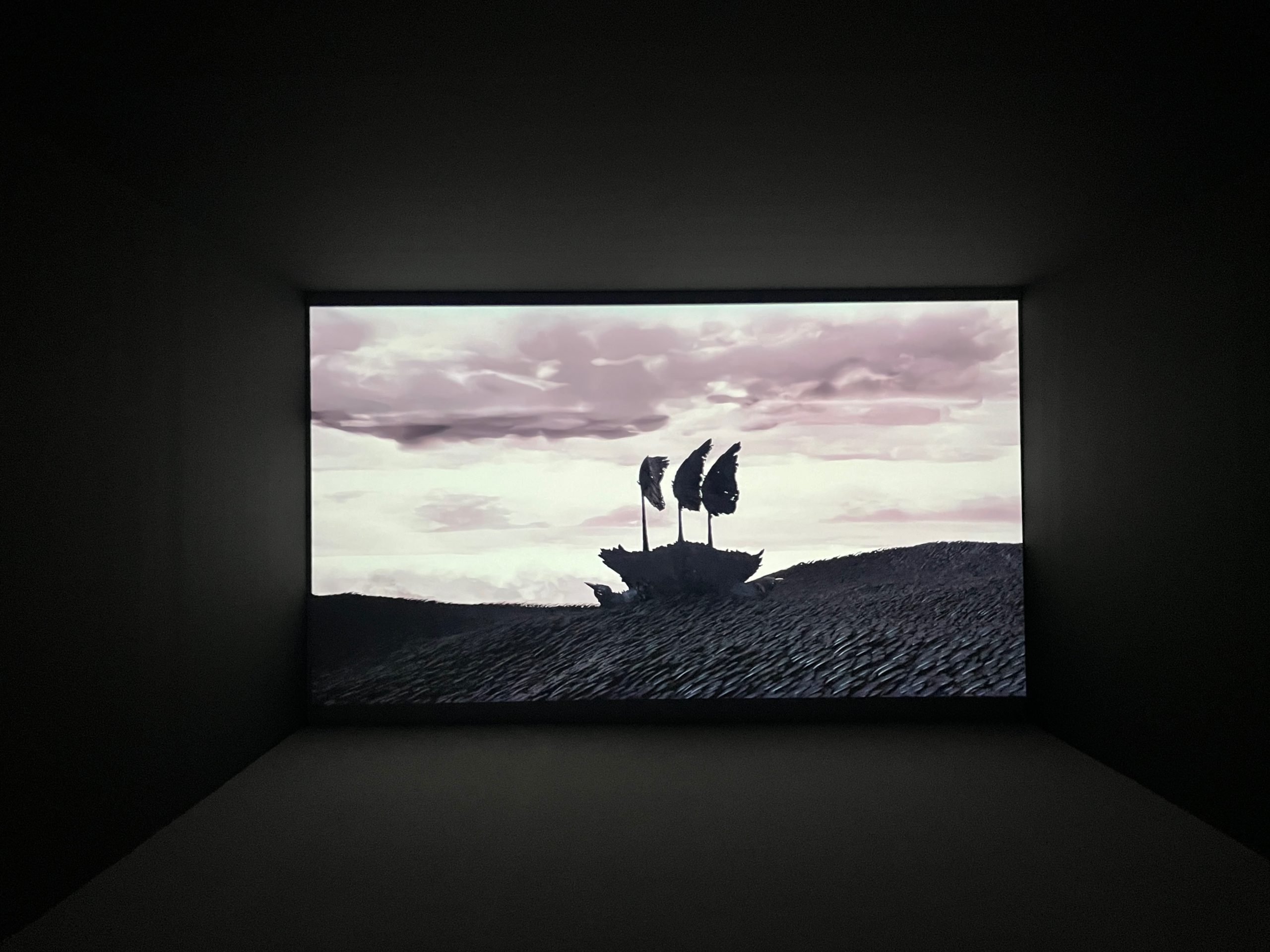 A simplified silhouette of a sailing ship floats along the water in a video projection