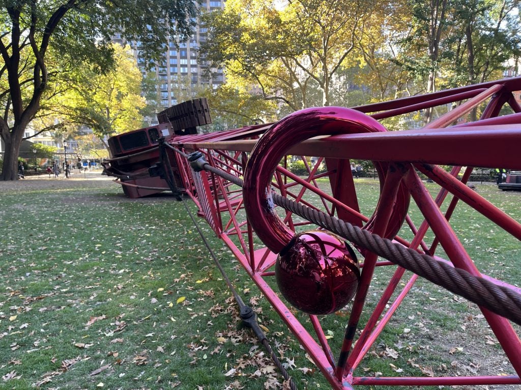 A large shiny magenta ring hangs on a long red crane’s beam.