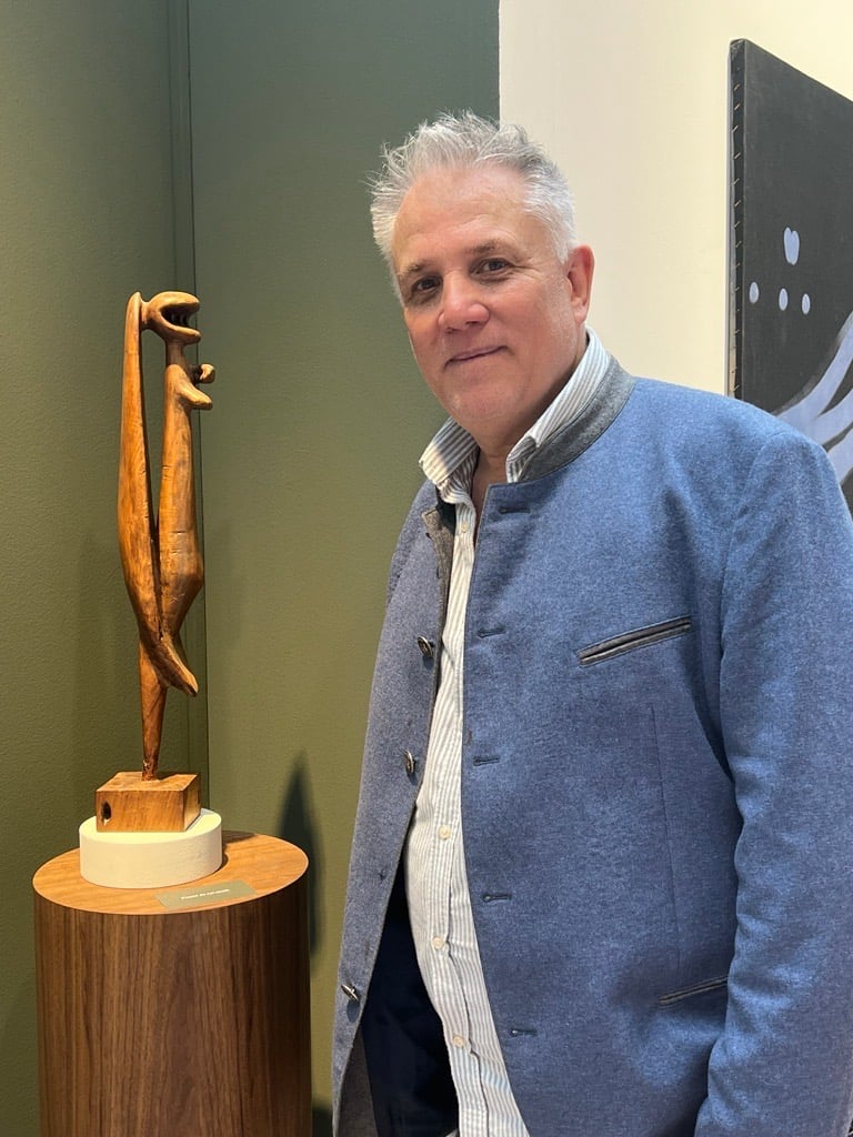 a white men next to a wooden sculpture