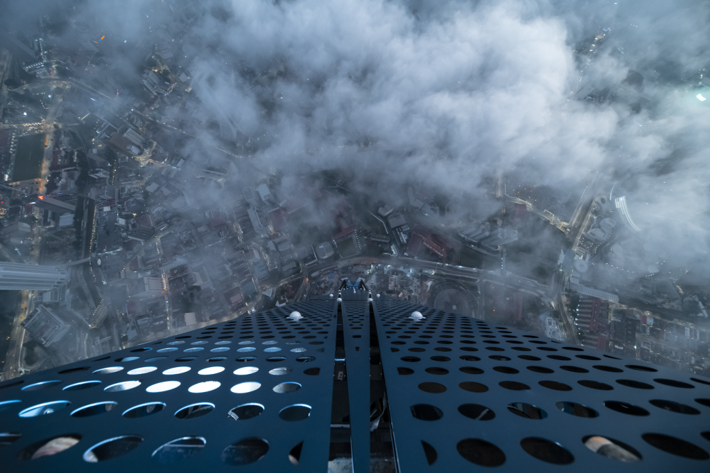 Isaac "Driftershoots" Wright's photograph of Merdeka PNB 118, the world's second-tallest building, in Kuala Lumpur, Malaysia. The photo looks down from the top of the skyscraper, the city below obscured by clouds many stories down. 