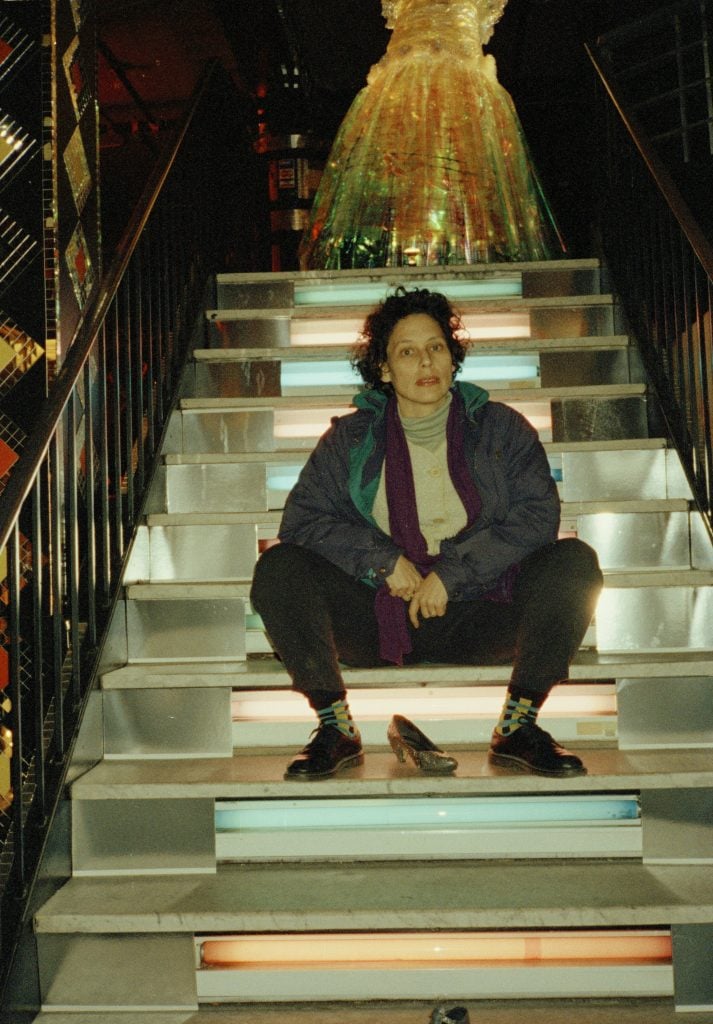 a woman sits on some steps. the photo is vintage