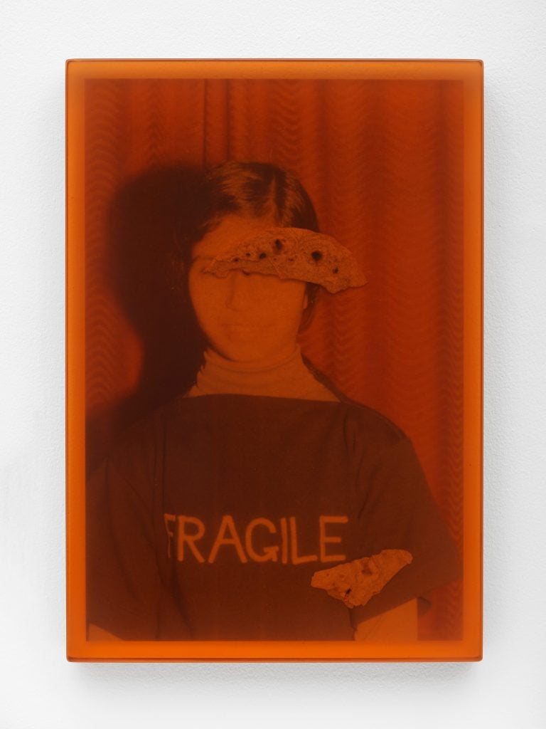 an orange tinted photo of a woman in a sweatshirt that says fragile on it