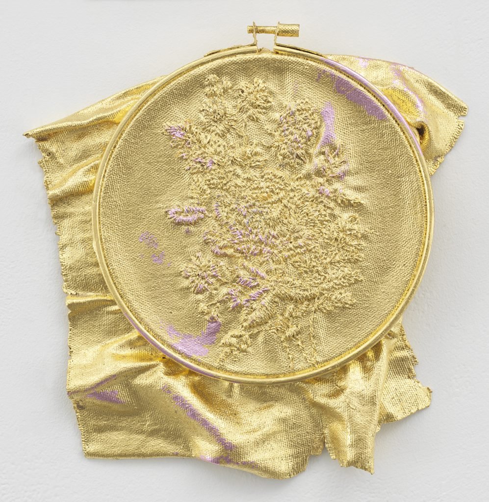 Jessie Henson, Monument (hold), 2024. A circular embroidery hoop with a floral design has been cast in bronze and coated with gold leaf.