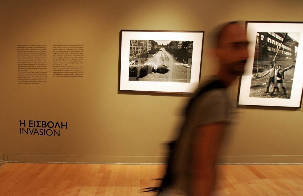 A man walks by a black and white photo of an arm with a watch in front of an empty street