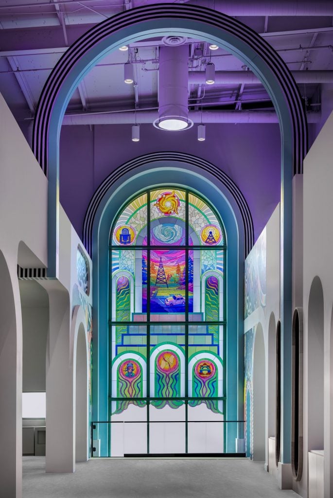 The entrance to Meow Wolf Radio Tave in Houston with a faux stained glass window featuring a radio tower.