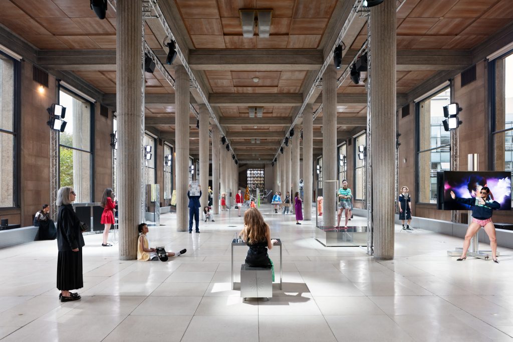 a vast industrial space with pillars populated with Miu Miu models