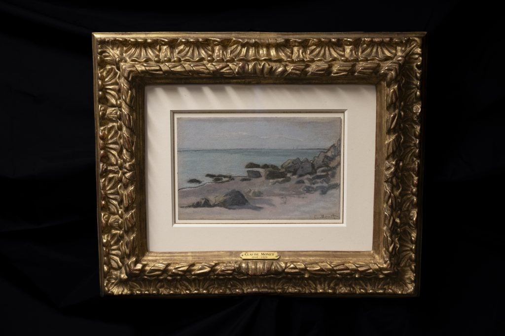 black background with painting in the center showing a seascape