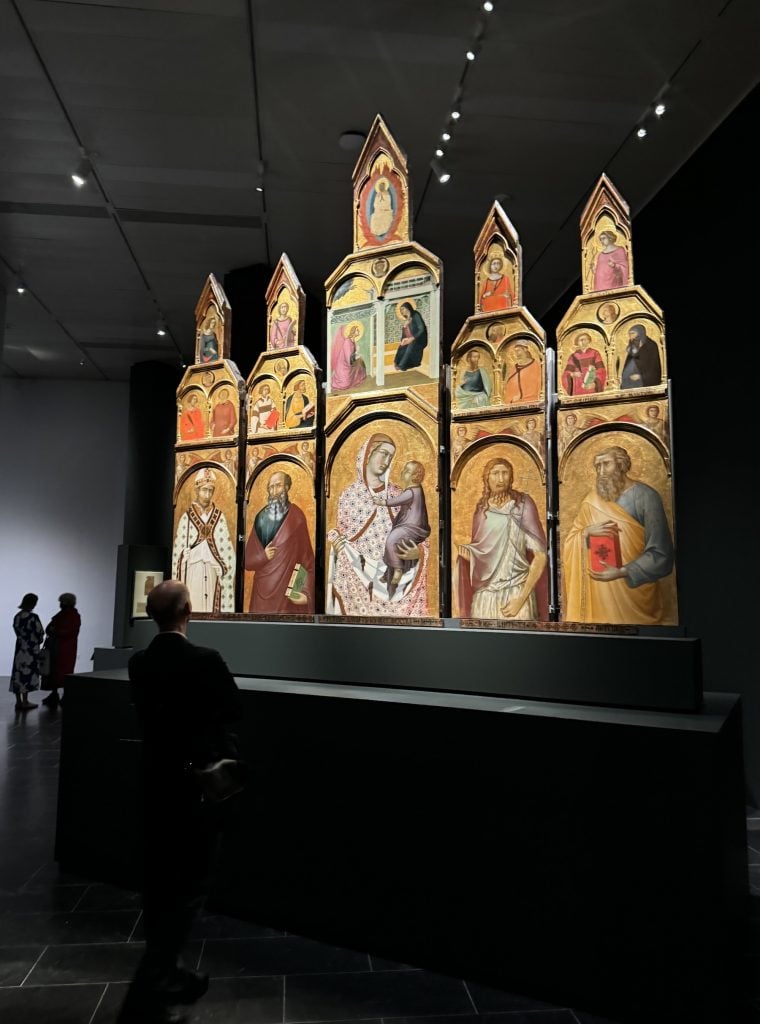 A man looks at a medieval altar in an art gallery