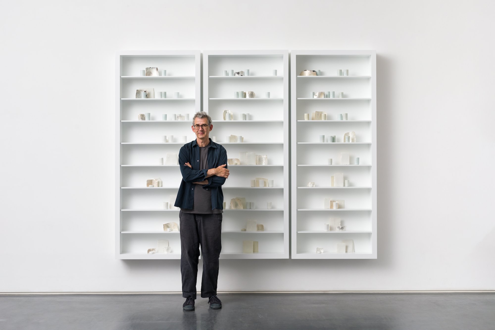 an image of the artist standing in front of a new work in his studio