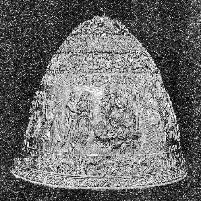 A detailed black-and-white illustration of the Tiara of Saitaphernes. The golden helmet features intricate reliefs depicting classical figures and scenes from ancient history, showcasing elaborate craftsmanship."