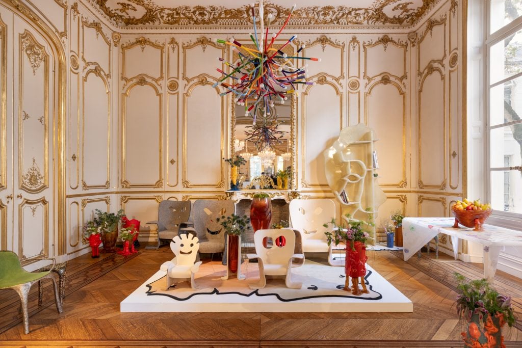 an ornate European room with white gilded walls is filled with design items 