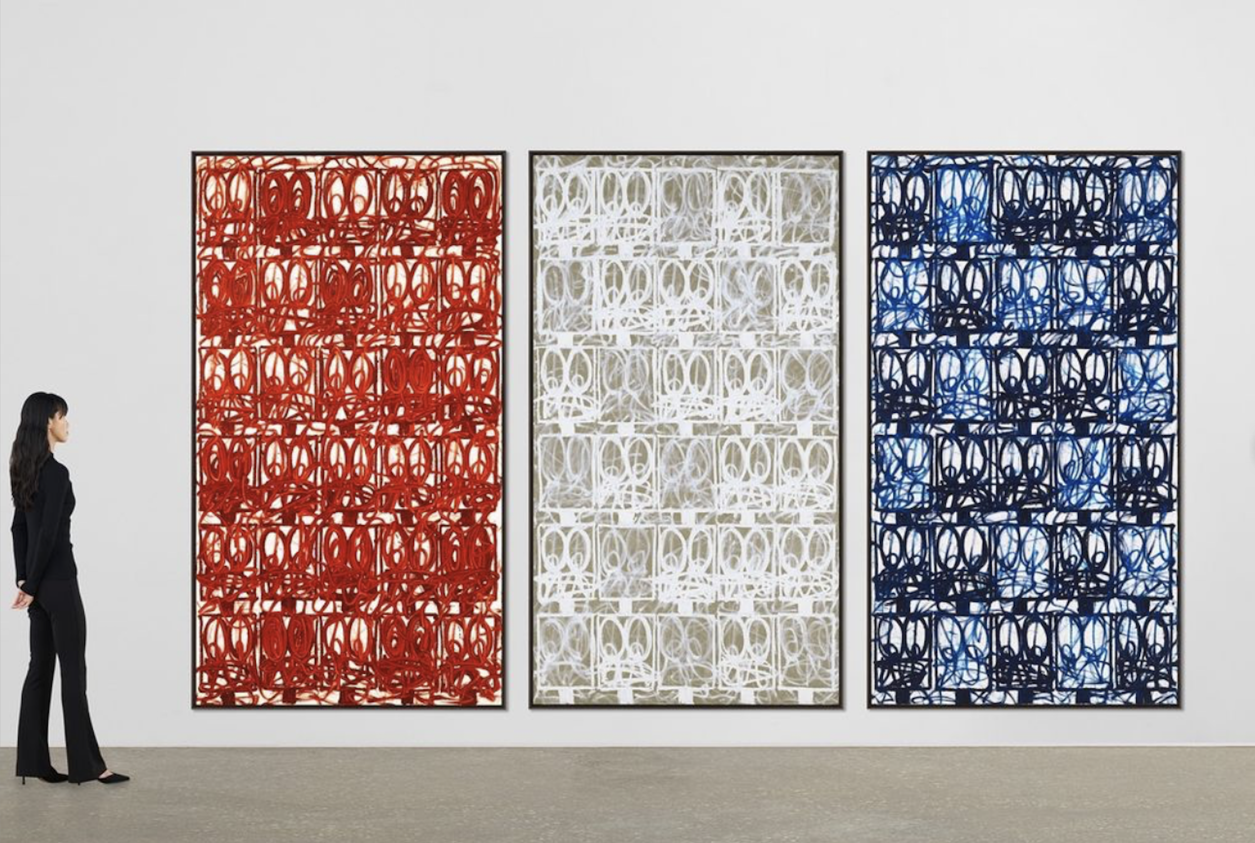 A photo of three abstract paintings—red, white, and blue—on a white wall