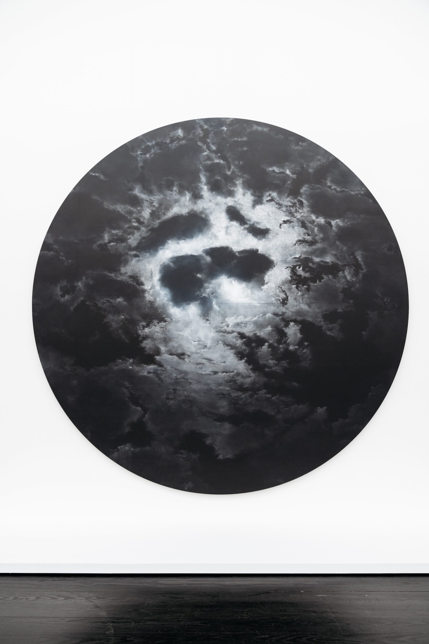 Tacita Dean, Delfern Tondo (2024), a round white chalk on blackboard drawing of the moon illuminating puffy clouds. 