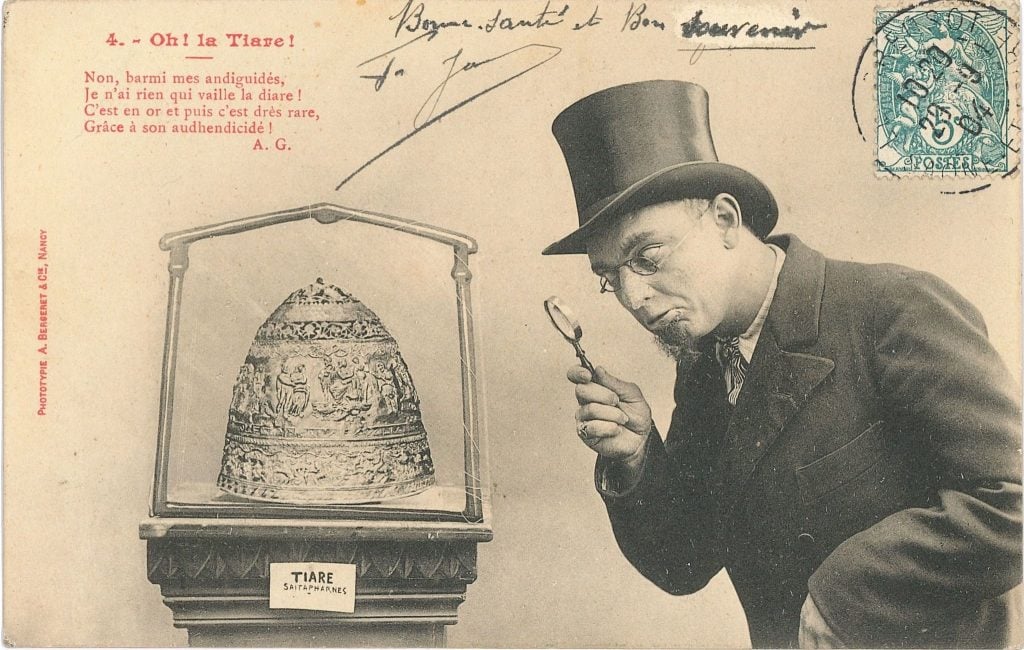 A vintage postcard showing a man in a top hat and glasses examining the Tiara of Saitaphernes with a magnifying glass. The tiara is displayed in a glass case labeled 'Tiare Saitapharnès'. A humorous rhyme in French is printed on the left side, making light of the tiara's authenticity. The postcard is stamped and signed, adding to its historical charm.