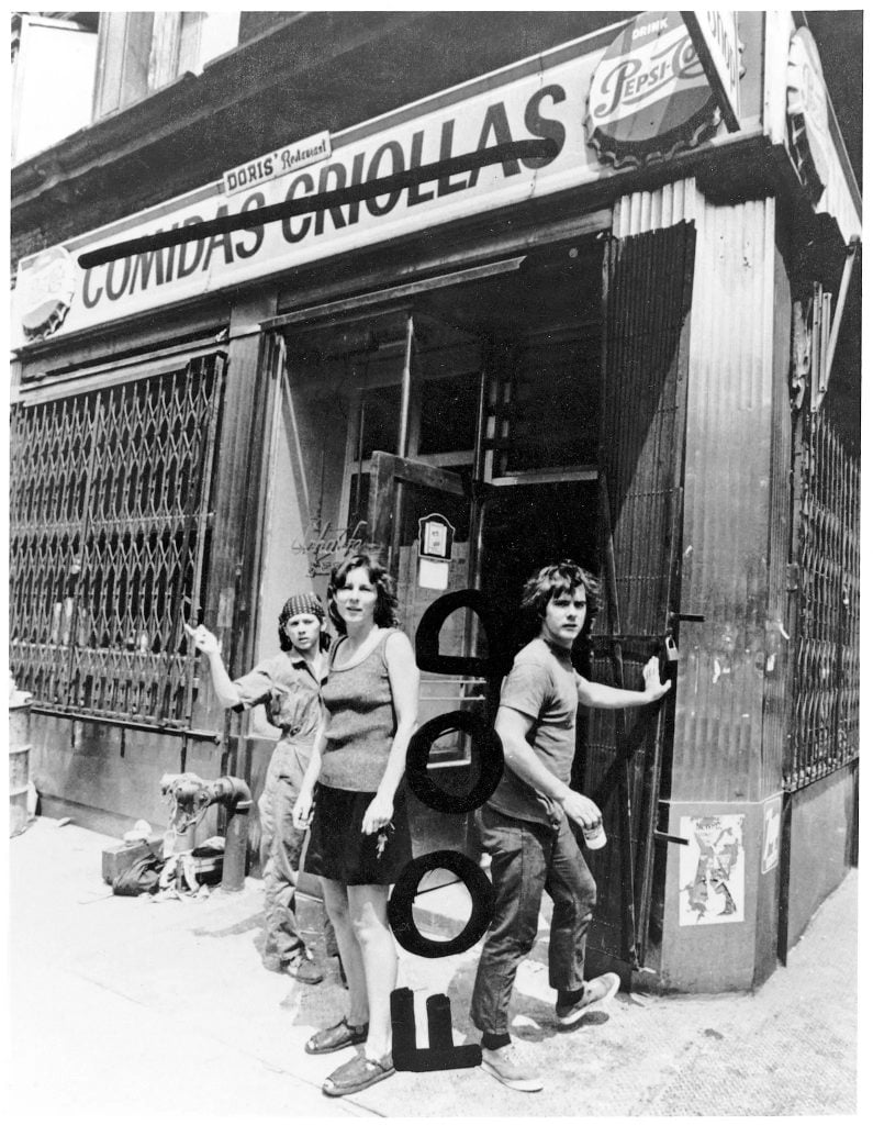 Richard Landry's black and white photo of Tina Girouard, Carol Goodden and Gordon Matta-Clark in front of Comidas Criollas, which was soon to become FOOD. Matta-Clarke wrote the new name on the print. 