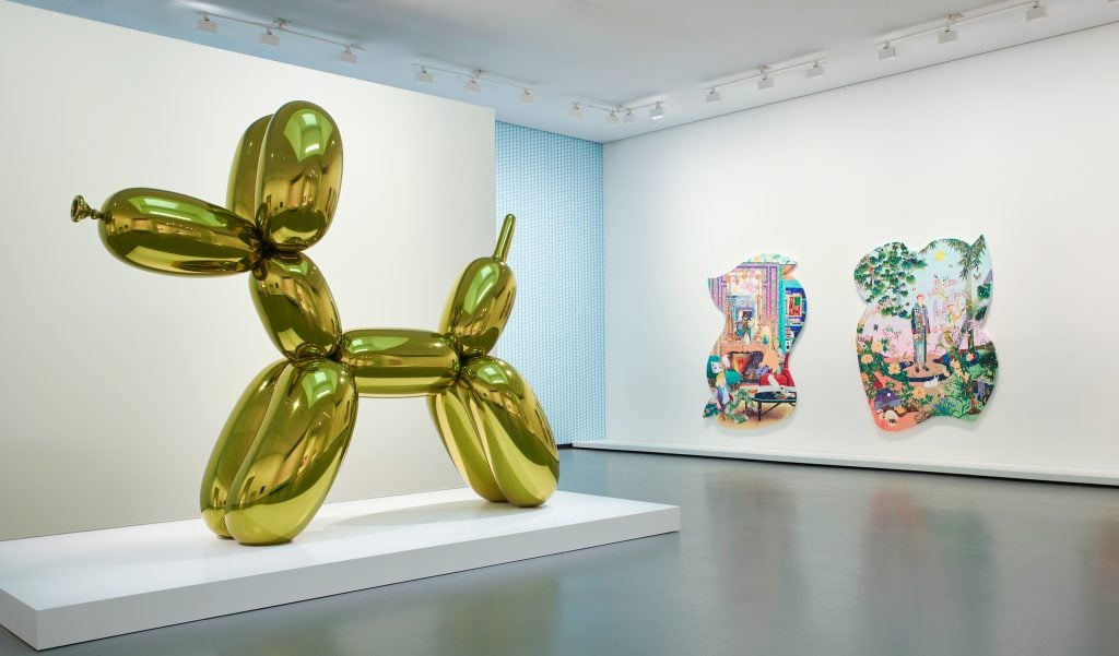 a large Jeff Koons sculpture of a yellow balloon dog is in a gallery 