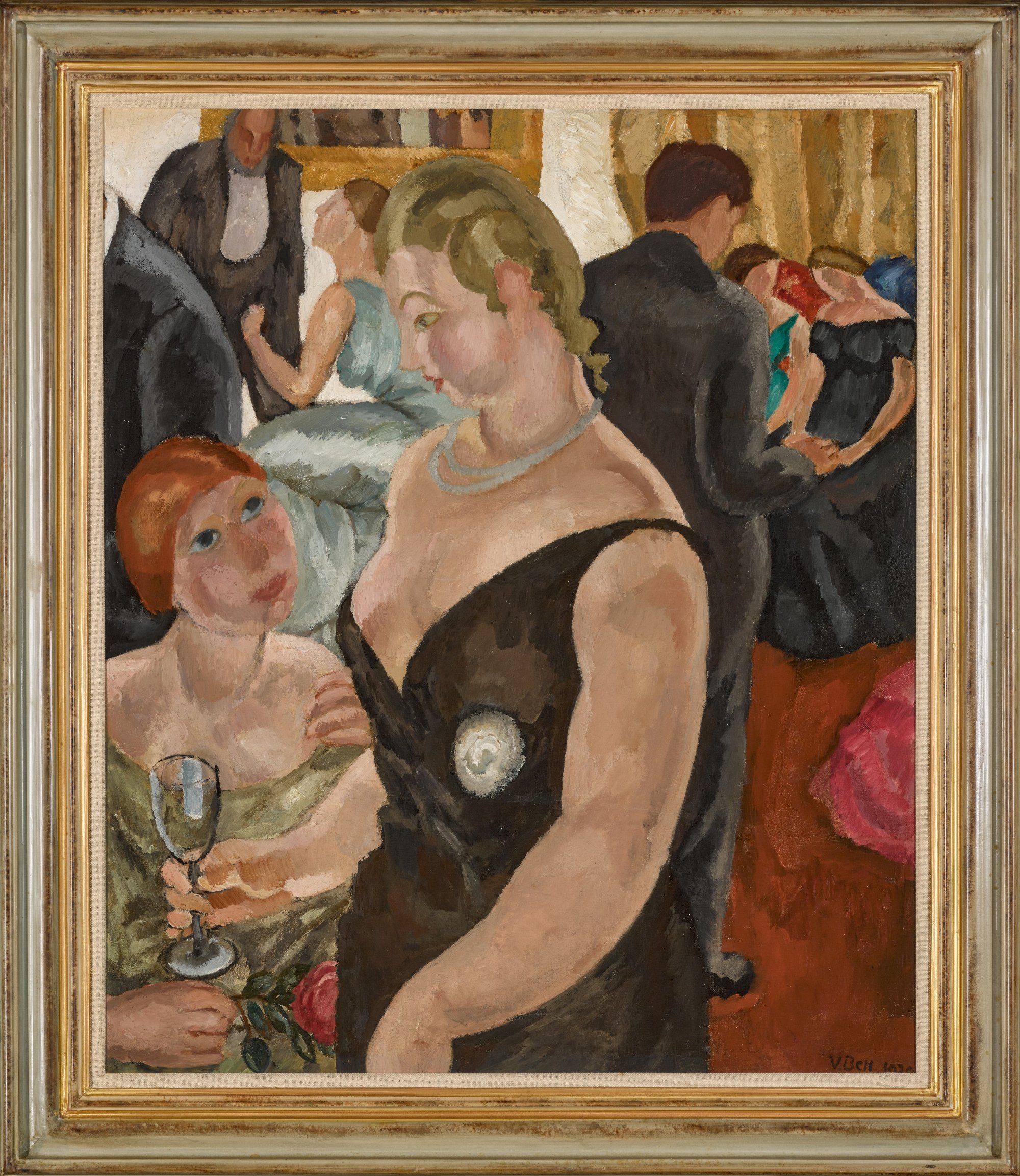 a framed painting of a party scene, in the foreground there are two women talking, one is seated and the other stands in a black dress holding a wine glass, people mill around in the backgground