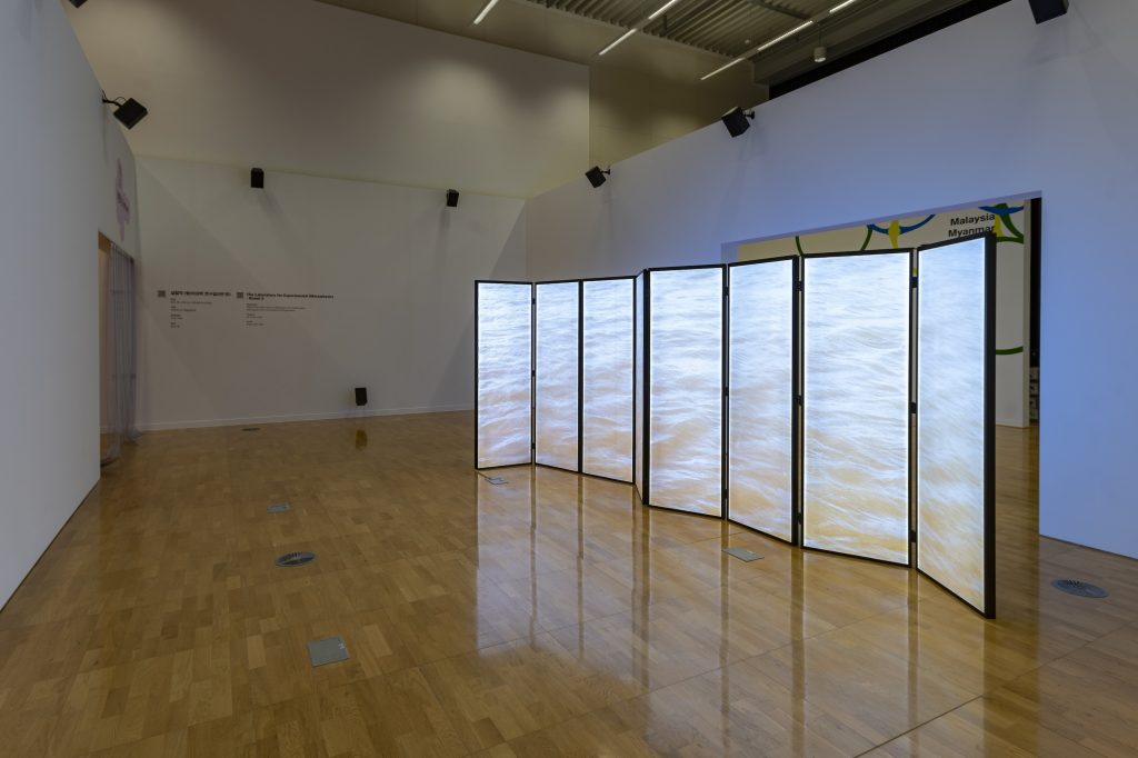 A glowing folding screen stands in the middle of a room