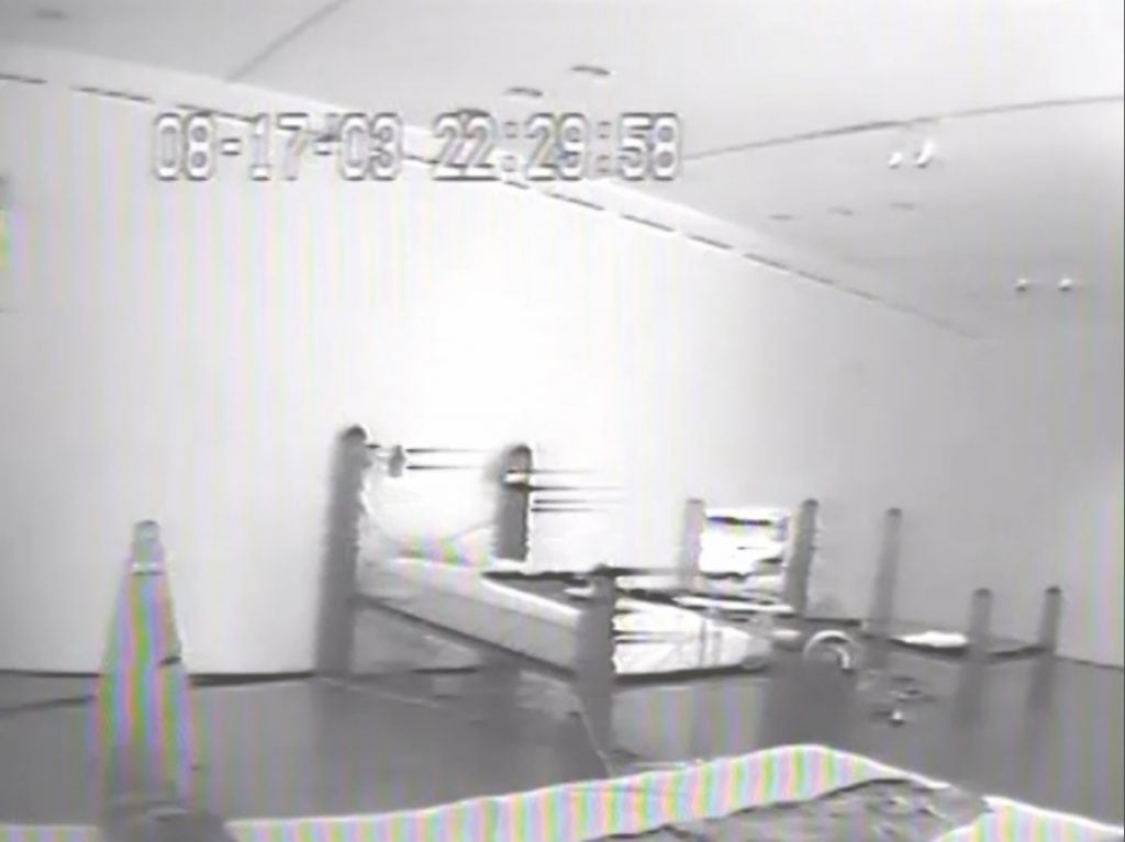 Black and white grainy CCTV footage screenshot of one of the beds by Agnes Scher.