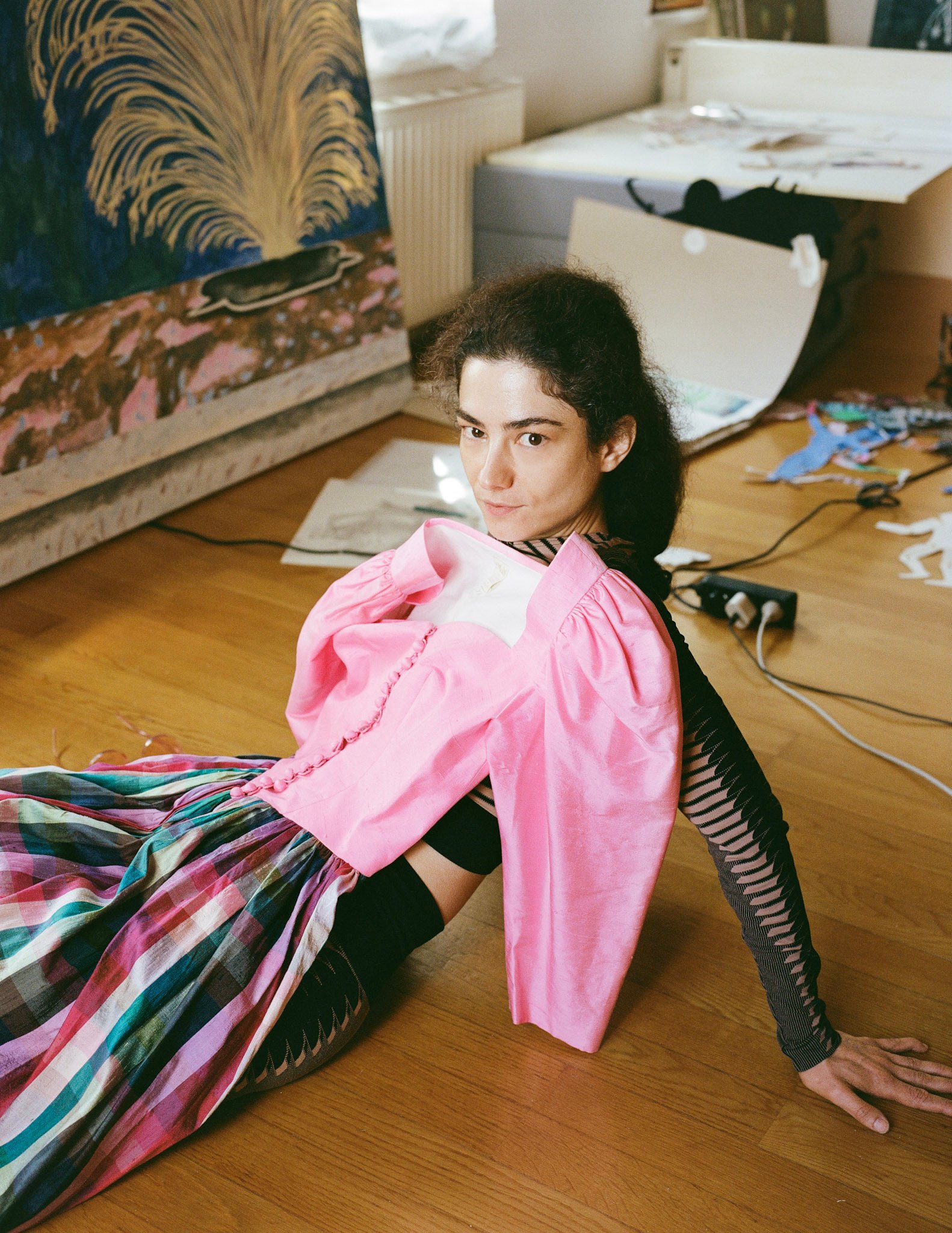 Portrait of artist Agnes Scherer leaning back on the ground with a dress with pink bodice and puffed sleeve and multicolor stripped skirt lain on top of her.