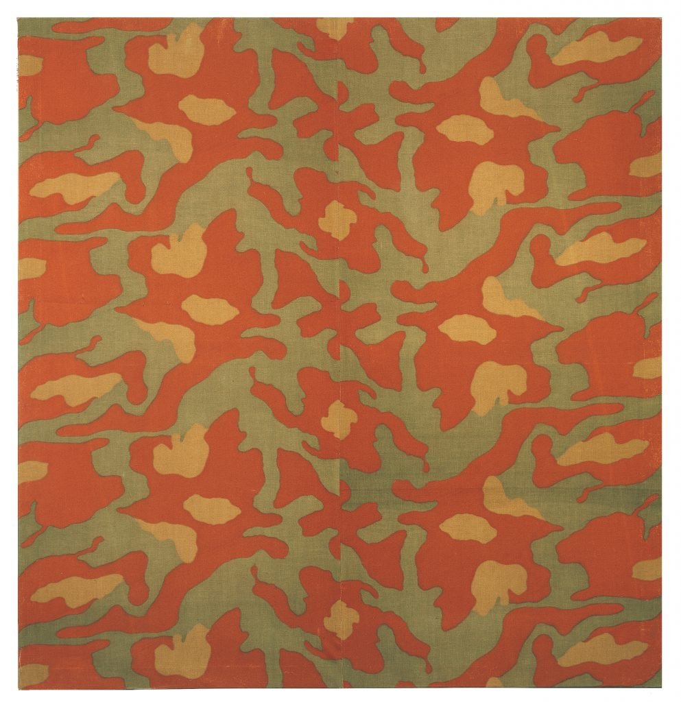 An abstract patterned work by Arte Povera artist Alghiero Boetti similar to camouflage in burnt orange, green, and ochre yellow.