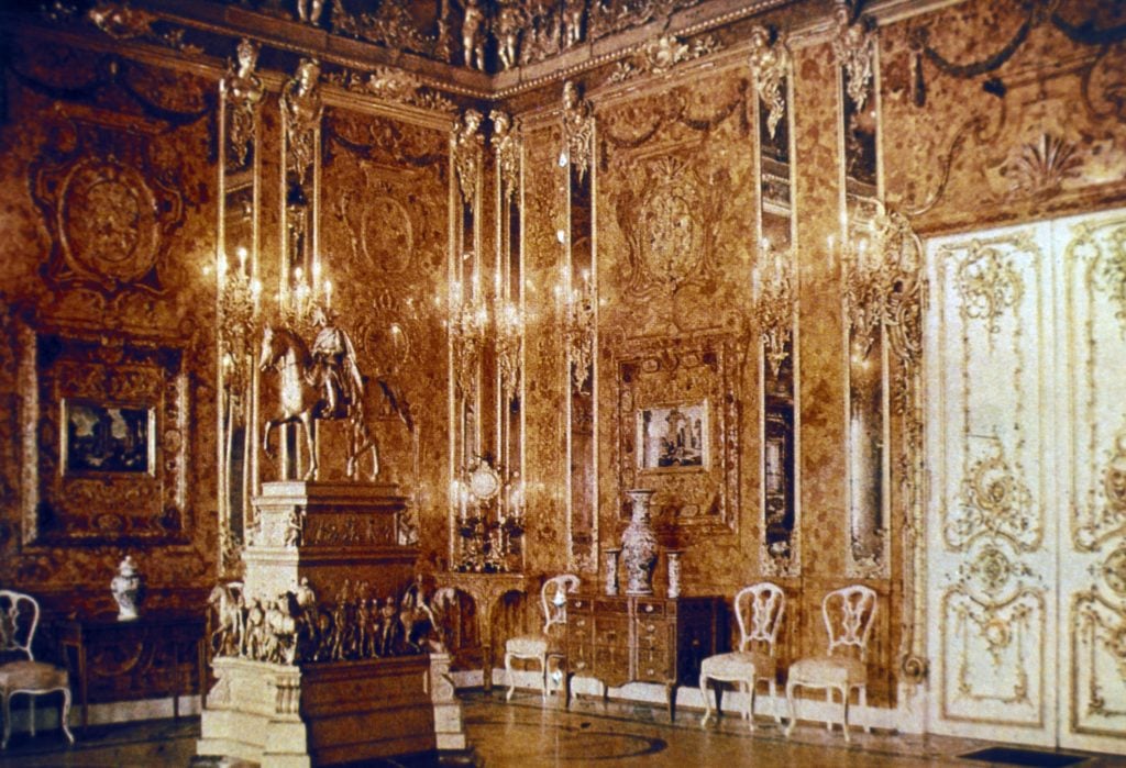 A room in a royal palace decorated throughout with amber and gold panels, with a sculpture of a horse standing in the middle