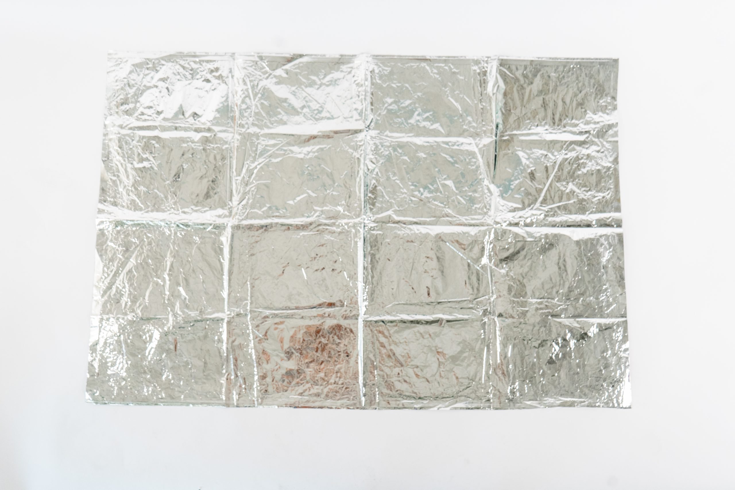 A deflated silver mylar balloon from an Andy Warhol artwork. It is lying flat but has creases from where it was folded into squares. 