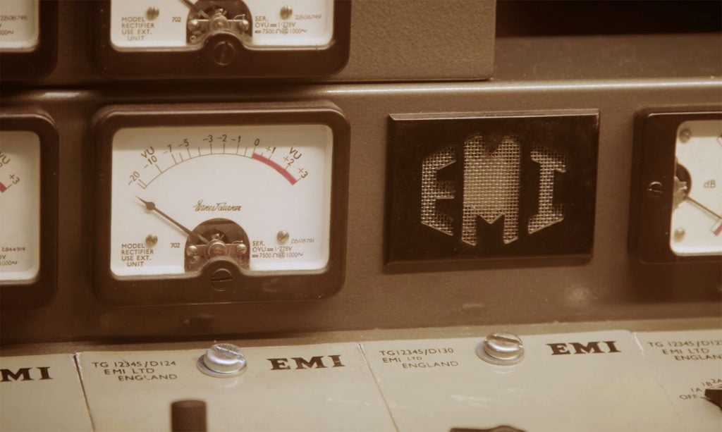 Close up of an analog recording console showing dials and the EMI logo